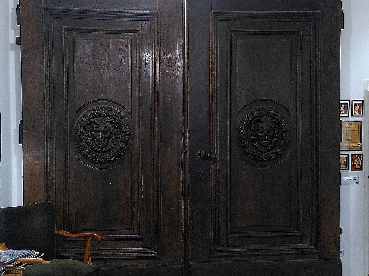 Die Holztore des ehemaligen Ringtheaters mit zwei geschnitzten Gesichtern (Komödie und Tragödie).