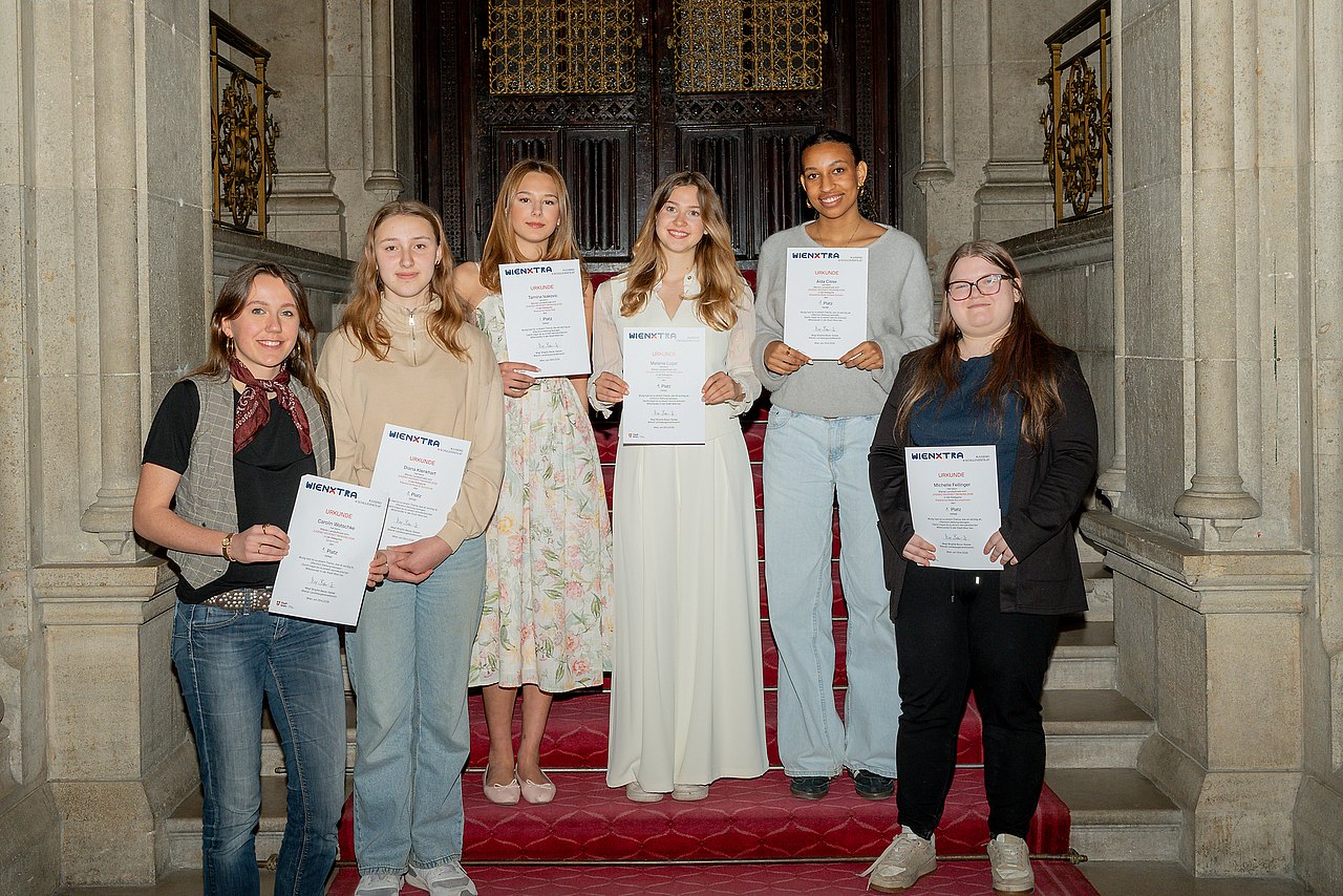 Die sechs Landesfinalistinnen vom Jugend-Redewettbewerb 2026 stehen mit ihren Urkunden auf einer Feststiege vom Rathaus.