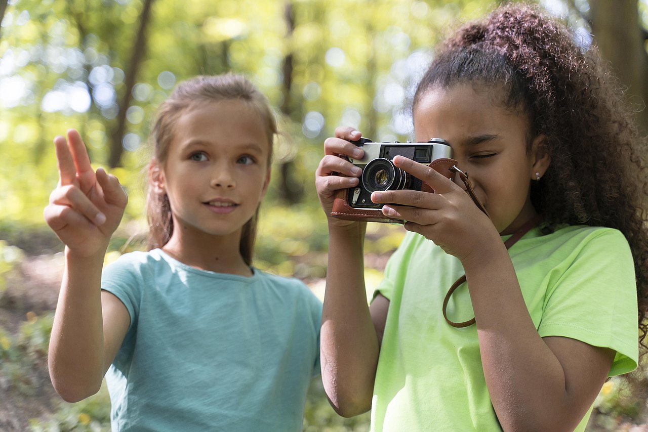 1 Mädchen fotografiert und 1 Mädchen zeigt was fotografiert werden soll