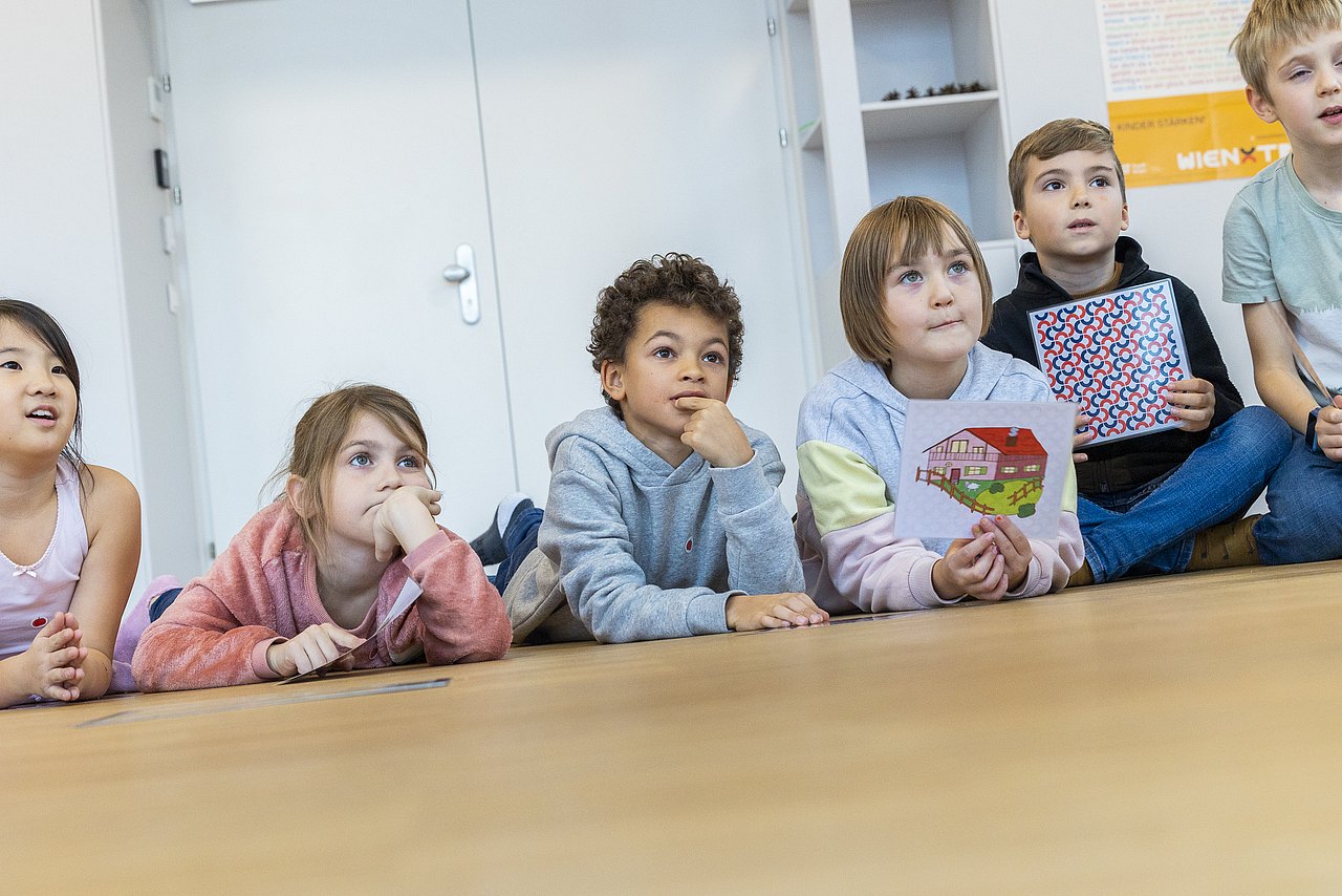 Kinder liegen am Boden und schauen in die Luft