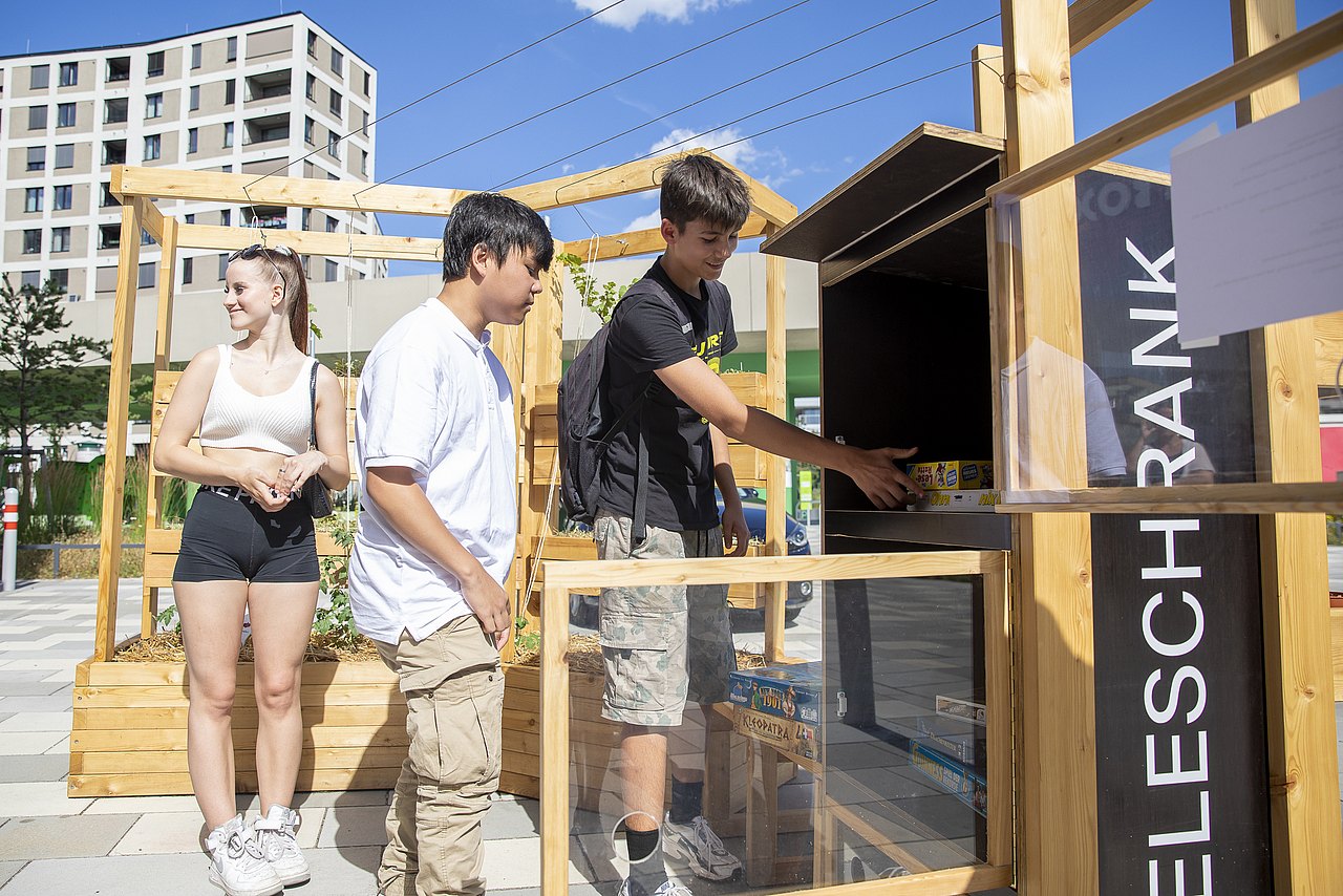 Jugendliche nehmen sich Spiele aus dem Spieletauschschrank