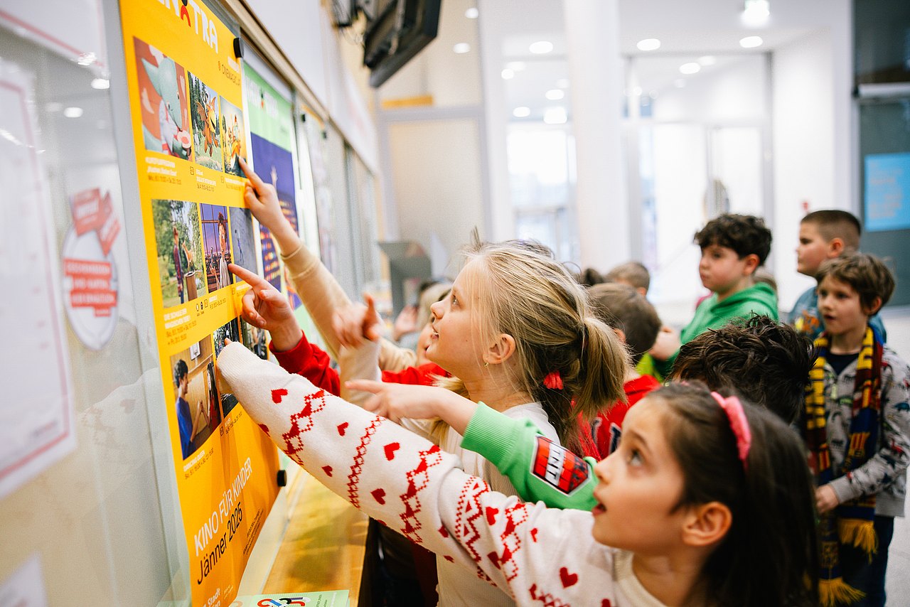 Kinder zeigen auf ein Plakat