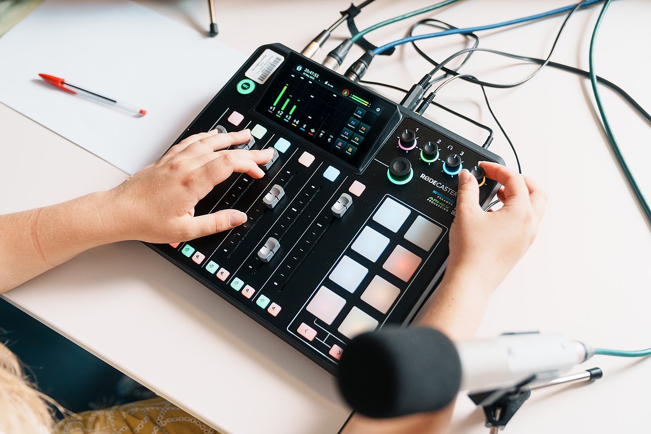 Eine Jugendliche bedient ein Audio-Mischpult, das auf einem Tisch liegt.