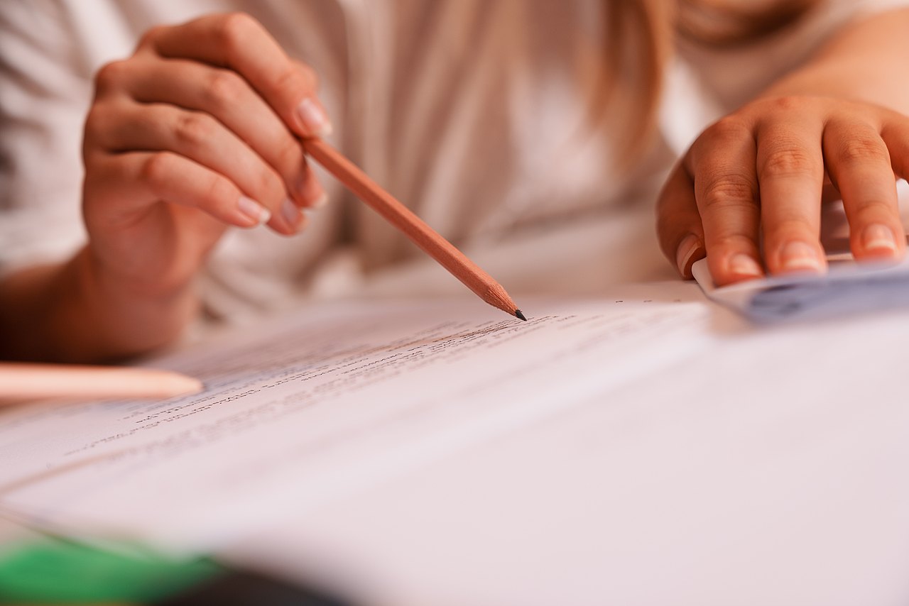 Mehrere Zettel liegen über einen Tisch verteilt. Eine Person liest die Zettel.