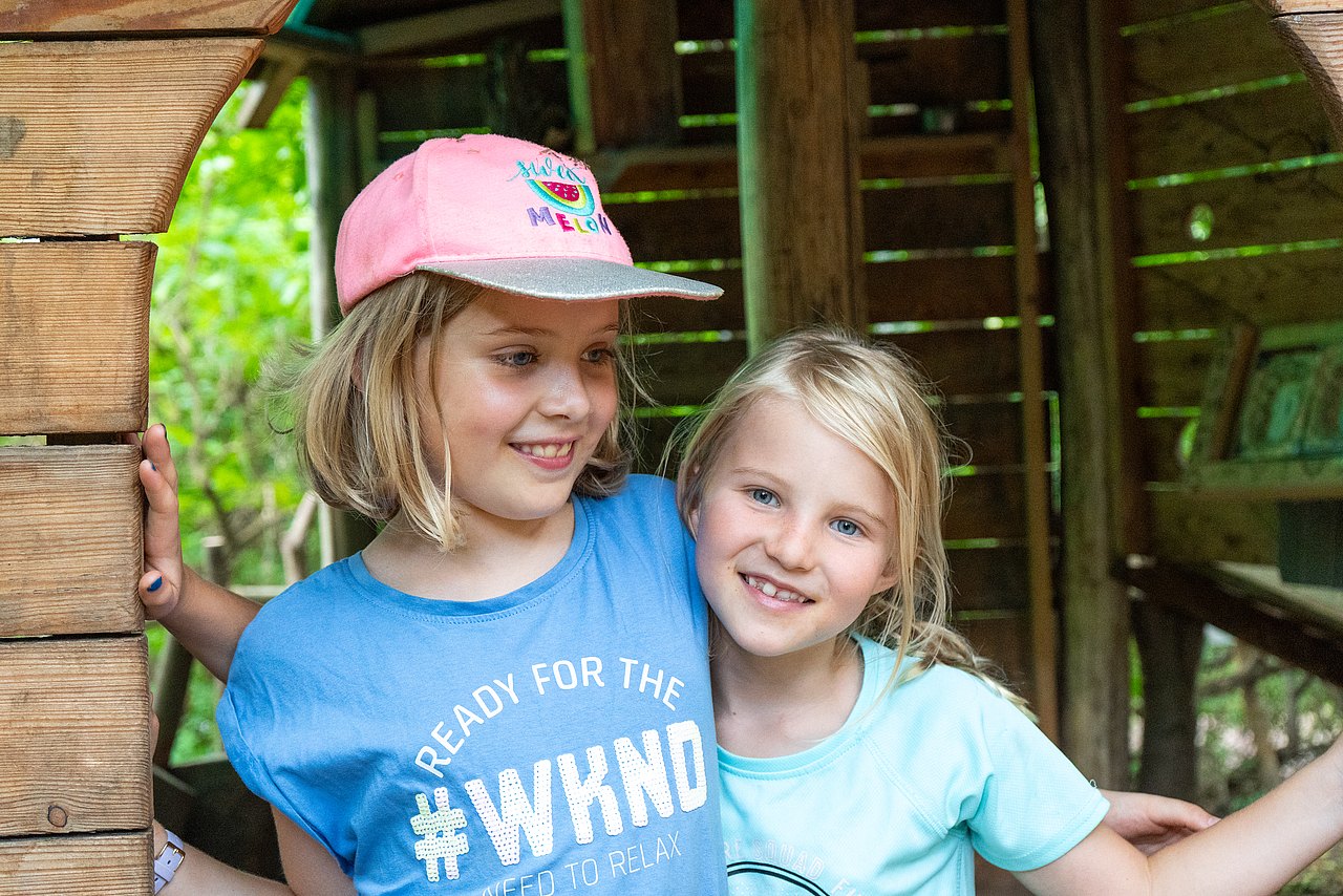 Das Foto zeigt zwei Kinder im Park in einer Holzhütte