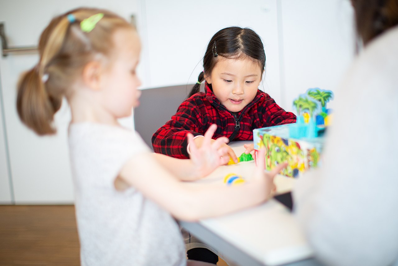 Zwei Mädchen sitzen an einem Tisch und spielen ein Brettspiel