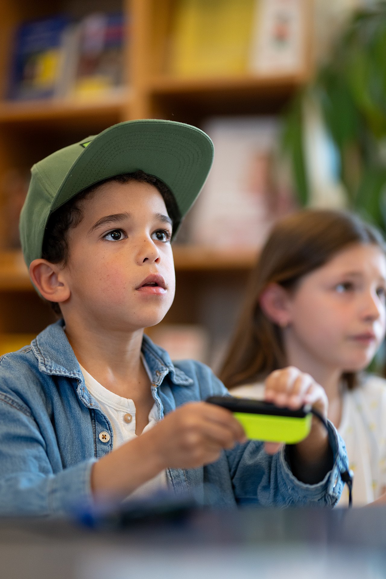 Kind mit Controller in der Hand schaut konzentriert auf den TV