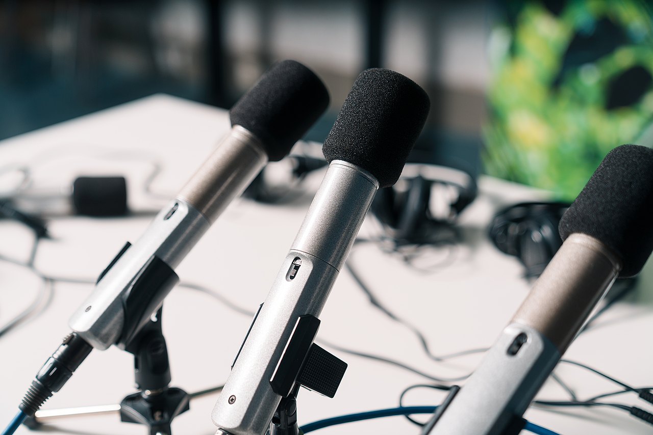 Drei Mikrofone stehen auf einem Tisch.