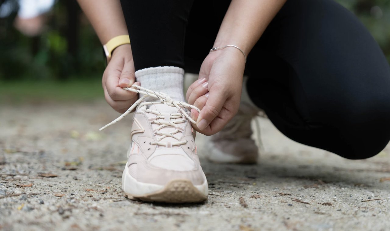 Eine junge Frau, die ihre Laufschuhe zuschnürt