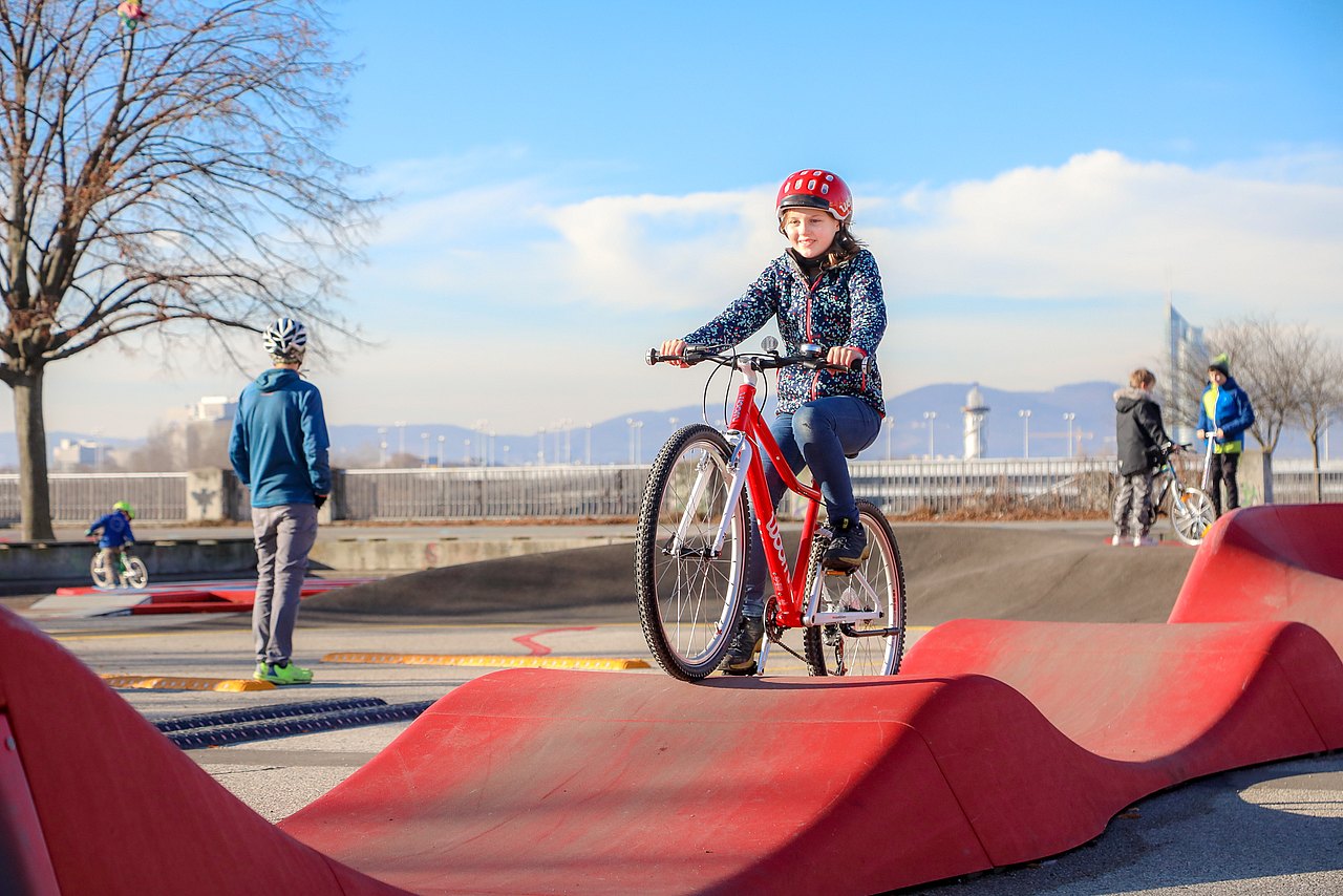 Wiener Radmotorikpark Ein Kind fährt mit Fahrrad über eine Wellenrampe.