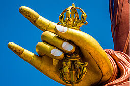 Hand von goldener Buddha-Statue macht Teufelsgruss