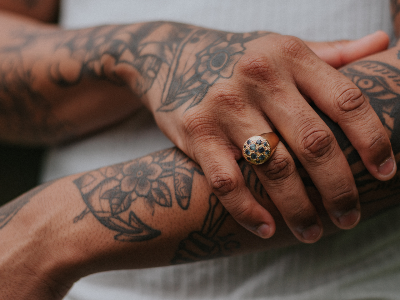 tättowierte Hände und Arme die vor dem Körper verschränkt sind