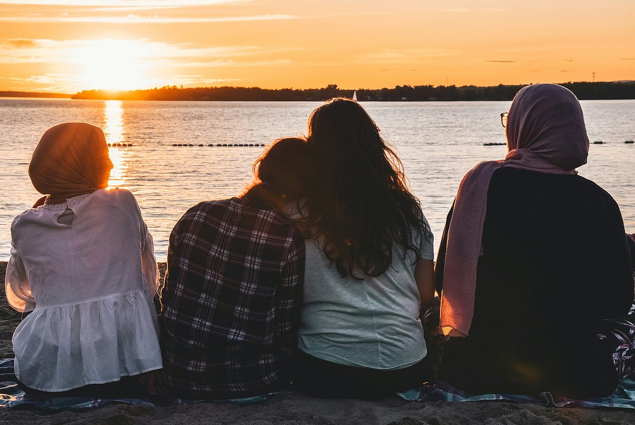 Vier Freund*innen schauen zusammen Sonnenuntergang