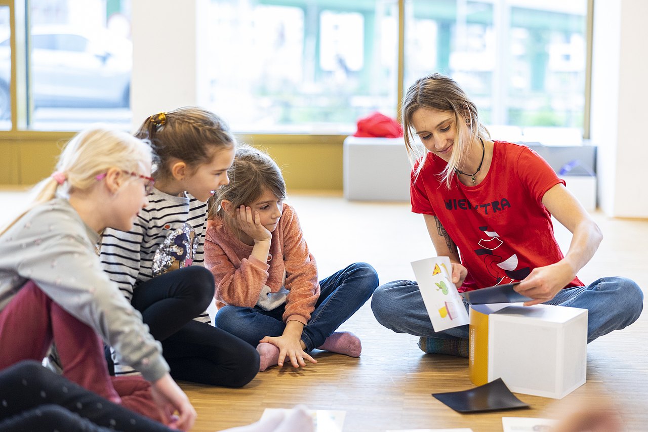 Kinder sitzen am Boden zusammen mit Workshopleitung und besprechen ein Thema