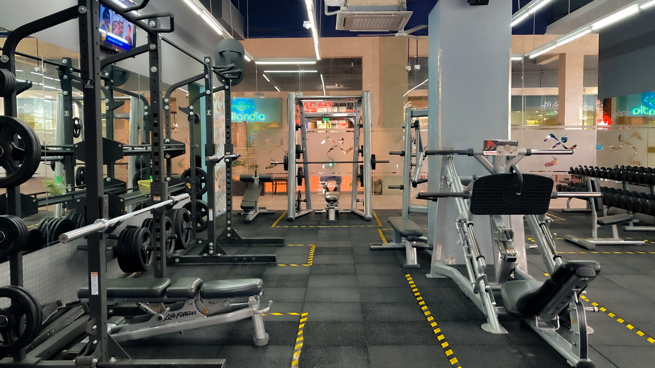 Modernes, gut beleuchtetes Fitnessstudio mit verschiedenen Krafttrainingsgeräten, ohne Personen.