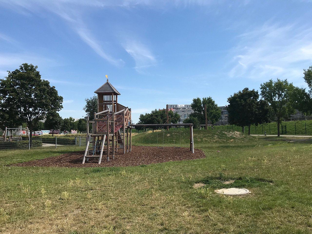 Klettergerät auf einer Wiese, im Hintergrund Häuserzeile