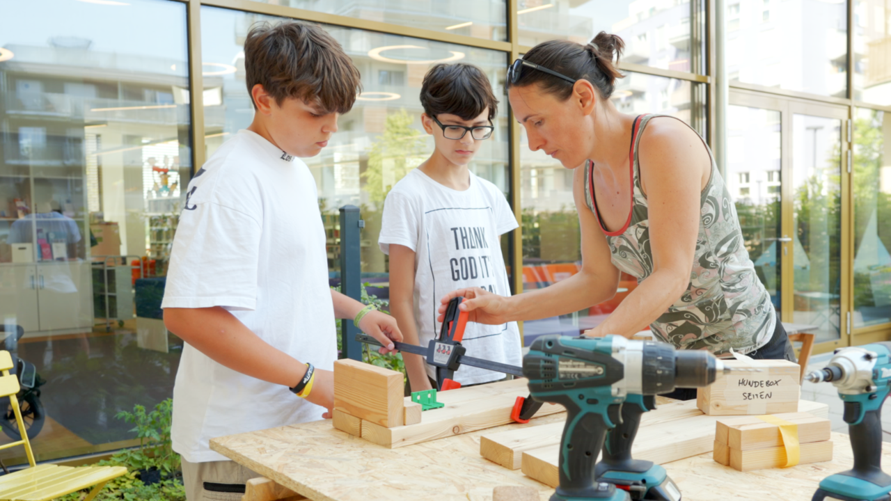 Jugendliche bauen mit Erwachsener mit Holz