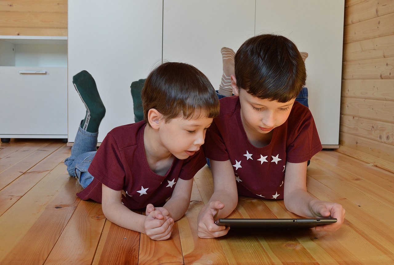 Handyfilm mit Kindern zwei Kinder am Boden liegend mit einem Tablet in der Hand