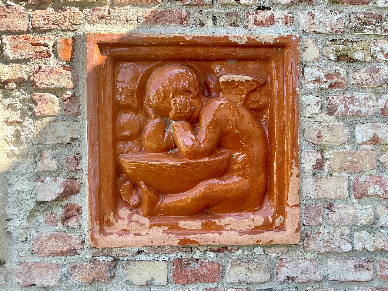 Detail am Spielplatz im Belbedere Garten Detailfoto einer braunen Relieffließe mit Kind über einer Schüssel am Spielplatz
