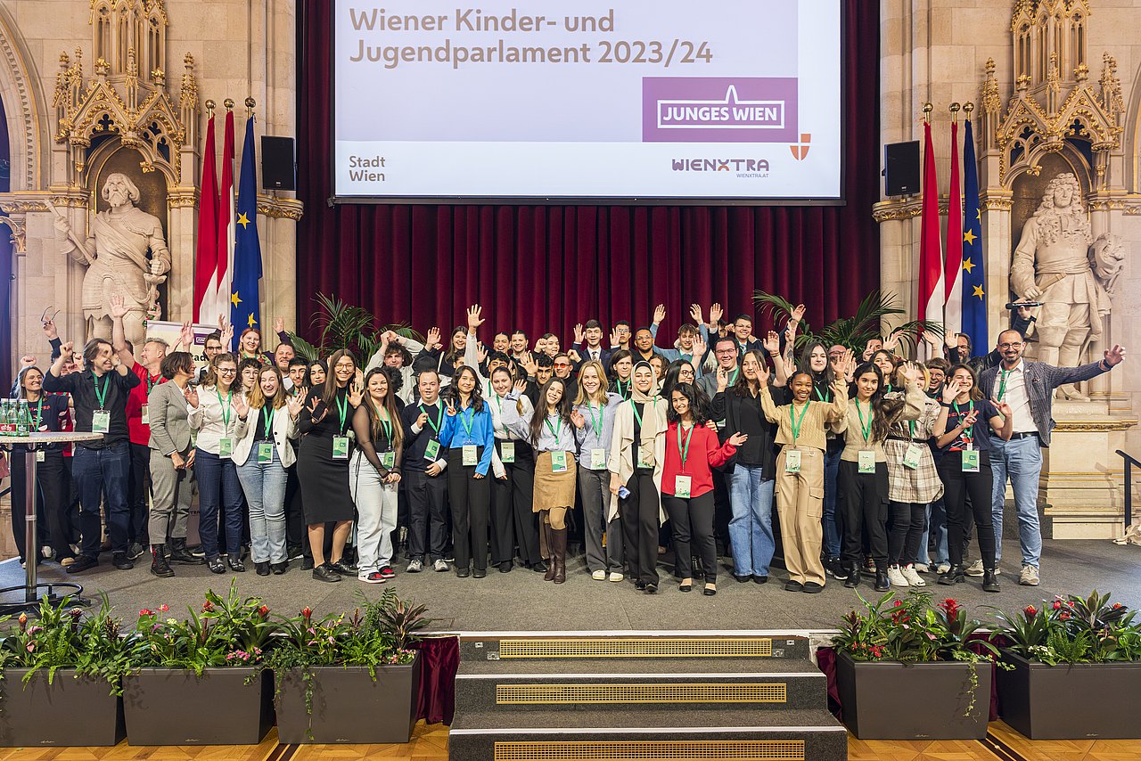 Junge Menschen stehen auf einer Bühne im Festsaal des Rathauses.