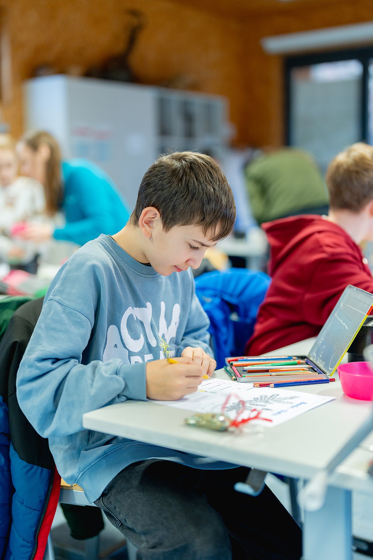 Schulkind sitzt an Tisch und schreibt