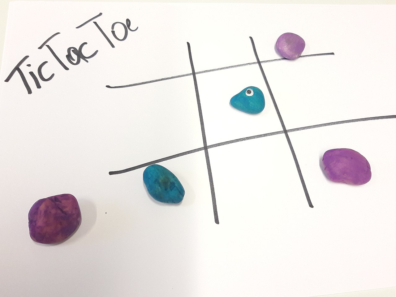 Tic Tac Toe Spiel mit bunten Steinen in Lila und Blau