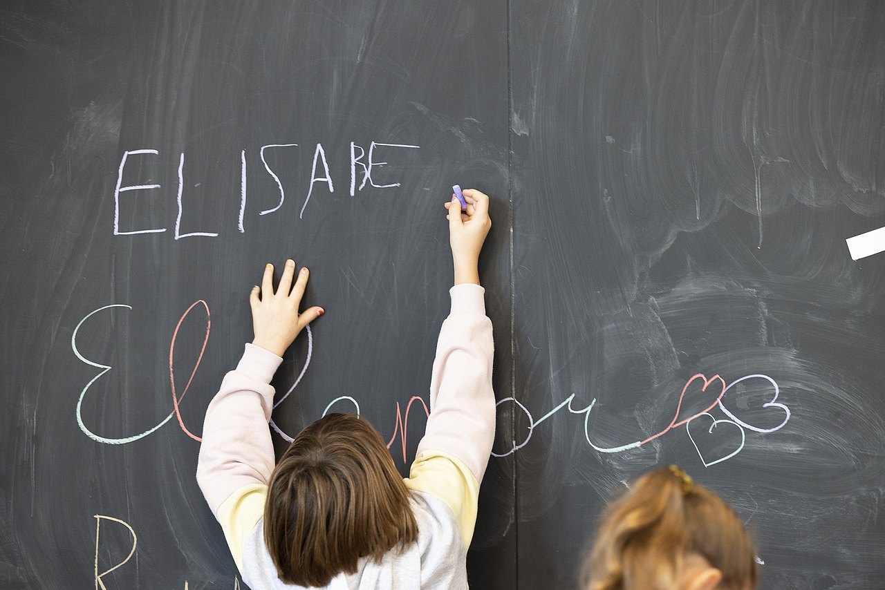 Kind schreibt etwas auf eine Tafel