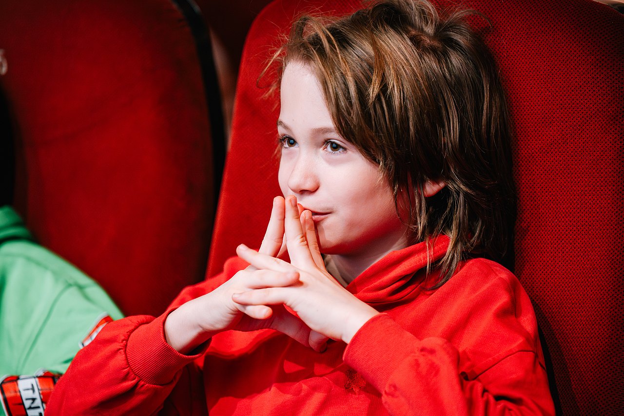 Mädchen im Kino schmunzelndes Mädchen in einem Kinosaal seitlich aufgenommen