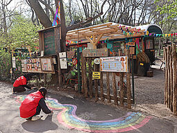 Zwei Jugendliche malen bunte Regenbögen mit Kreide vor dem Cafe Regenbogen.