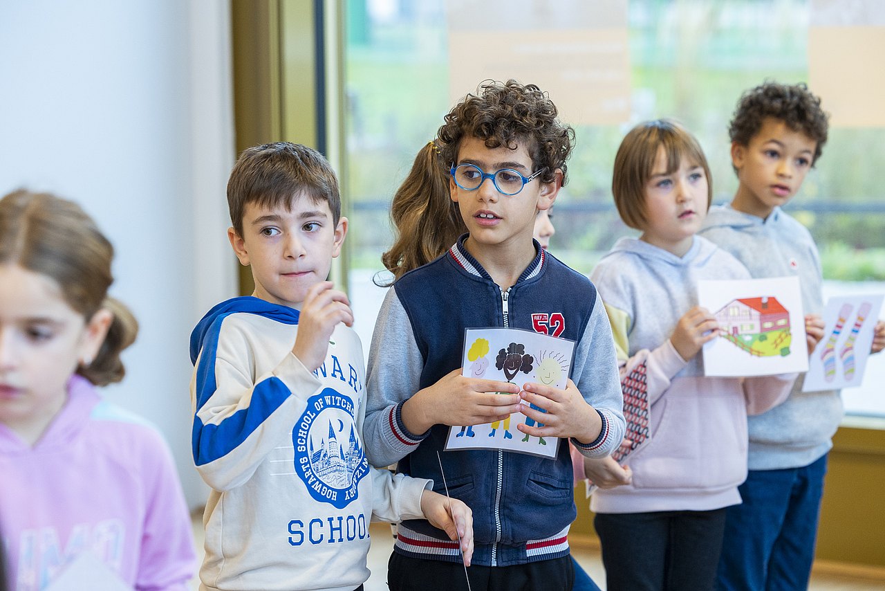 Kinder im Volksschulalter, teilweise mit Zeichnungen in den Händen