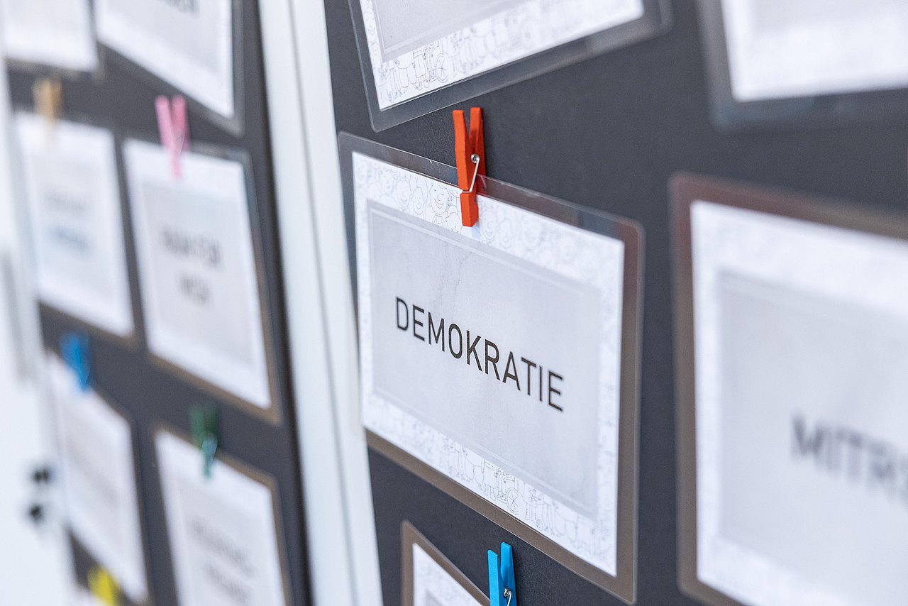Schild mit Wort Demokratie neben anderen Schildern