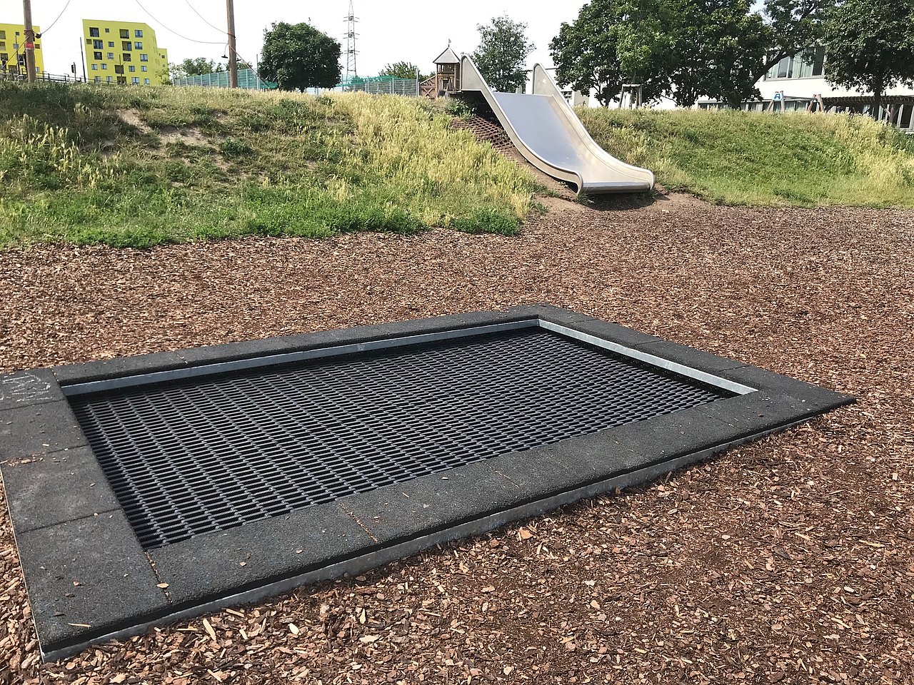 Bioden-Trampolin auf Rindenmulchh, im Hintergrund breite hangrutsche