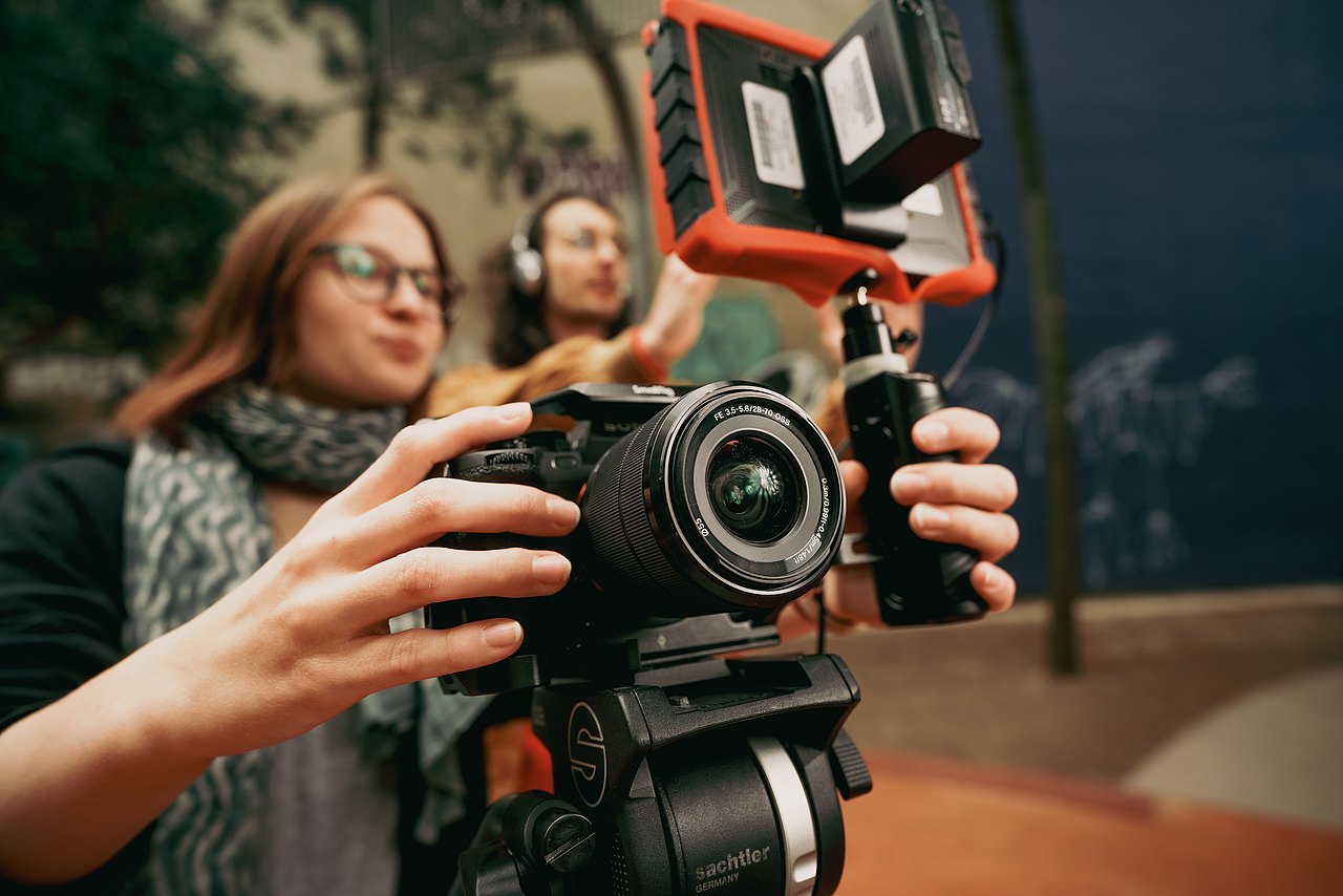 Eine Jugendliche bedient eine professionelle Sony-Kamera mit einem externen Monitor auf einem Stativ.
