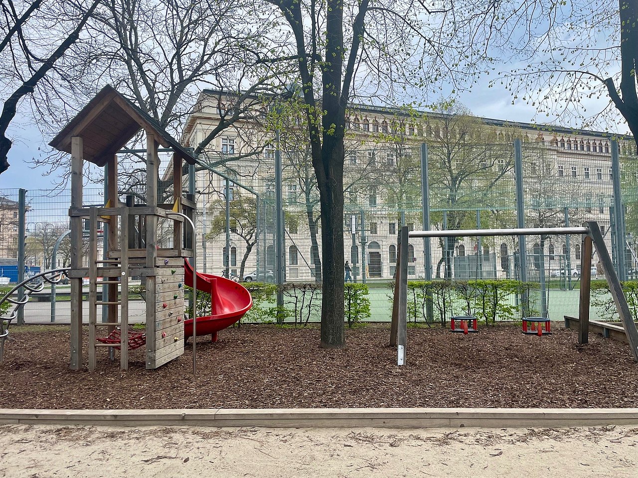 Kletteranlage und Kleinkinderschaukeln am Spielplatz Weghuberpark Klettertrum mit kleiner Bolderwand und Rutsche sowie 2 Kleinkinderschaukelkörbe