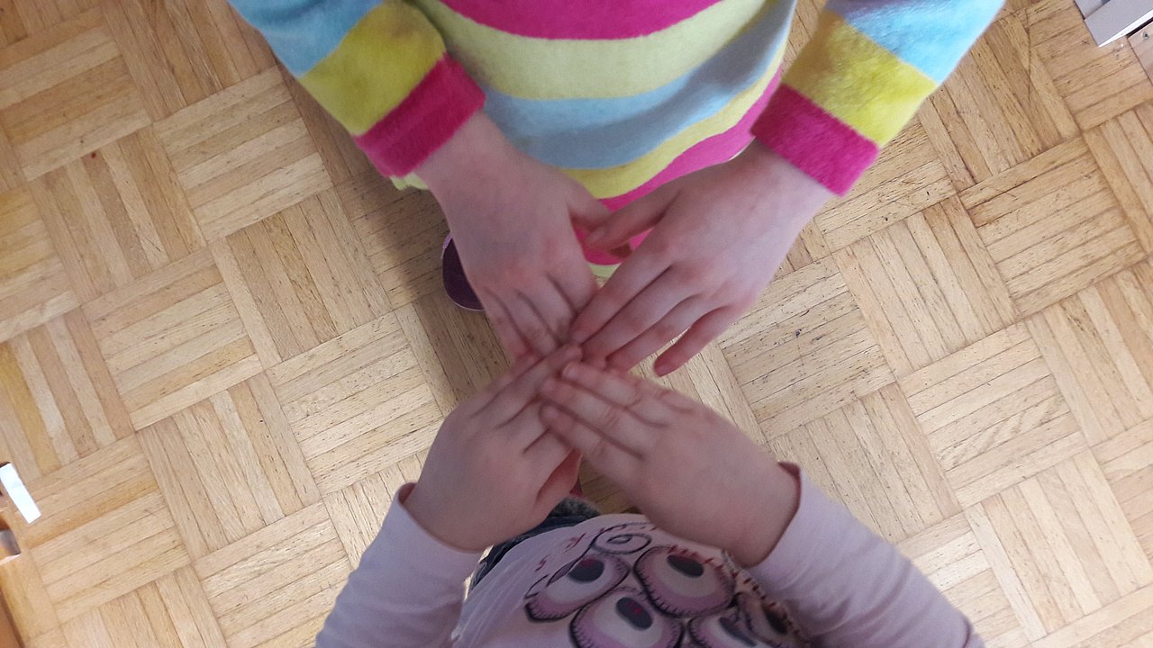 Zwei Kinder haben die Fingerspitzen übereinander gelegt, sodass ihre Hände ein X ergeben.