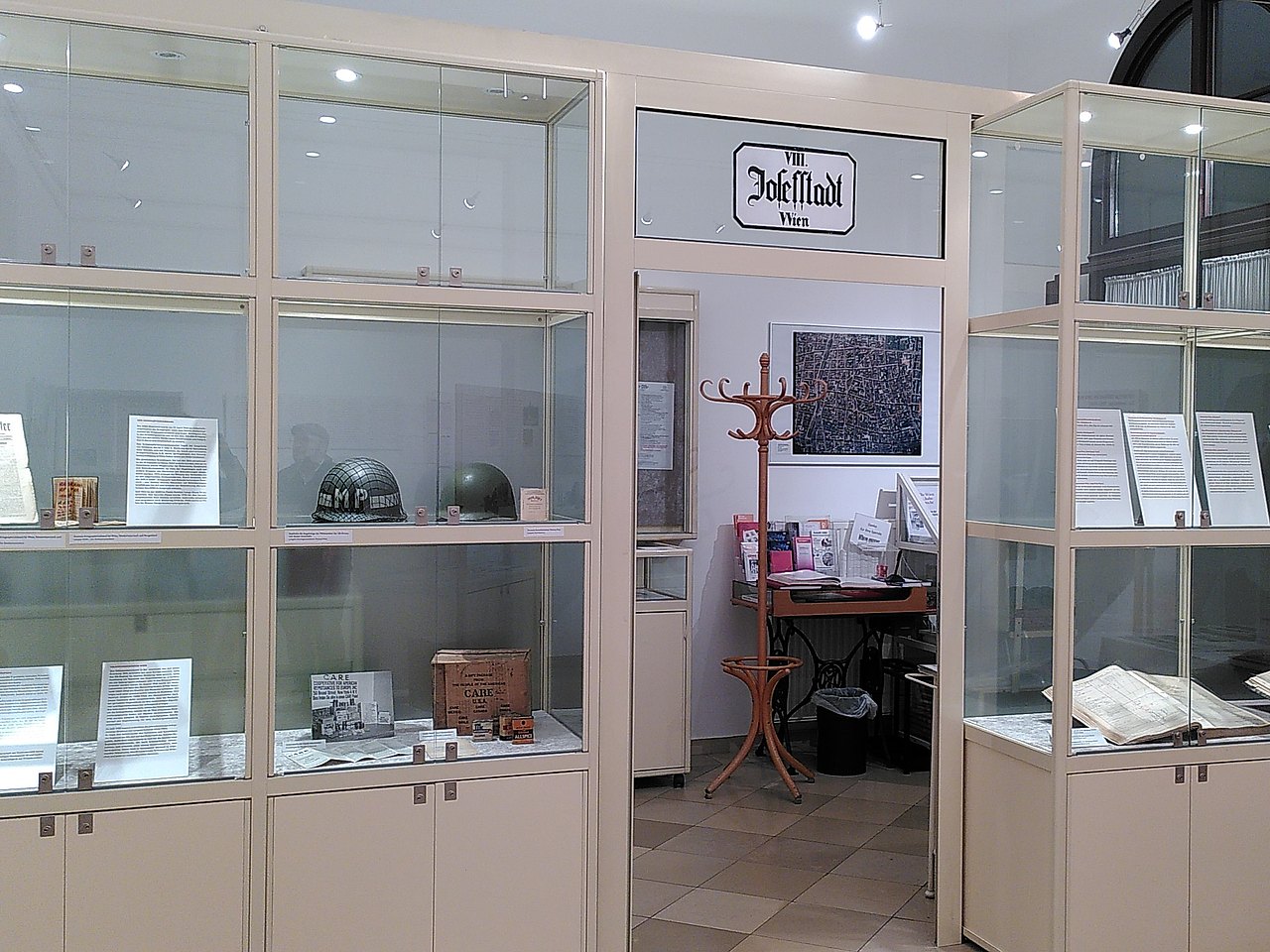 Ausstellungsraum des Bezirksmuseums Josefstadt mit Schaukästen mit Infotafeln und 2 Soldatenhelmen.