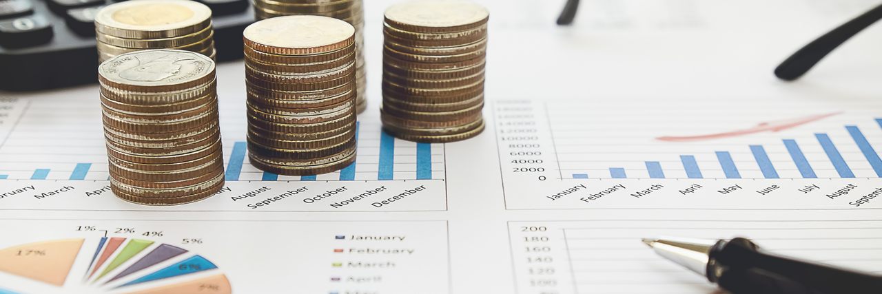 Münzen liegen auf einem Zettel mit Berechnungen