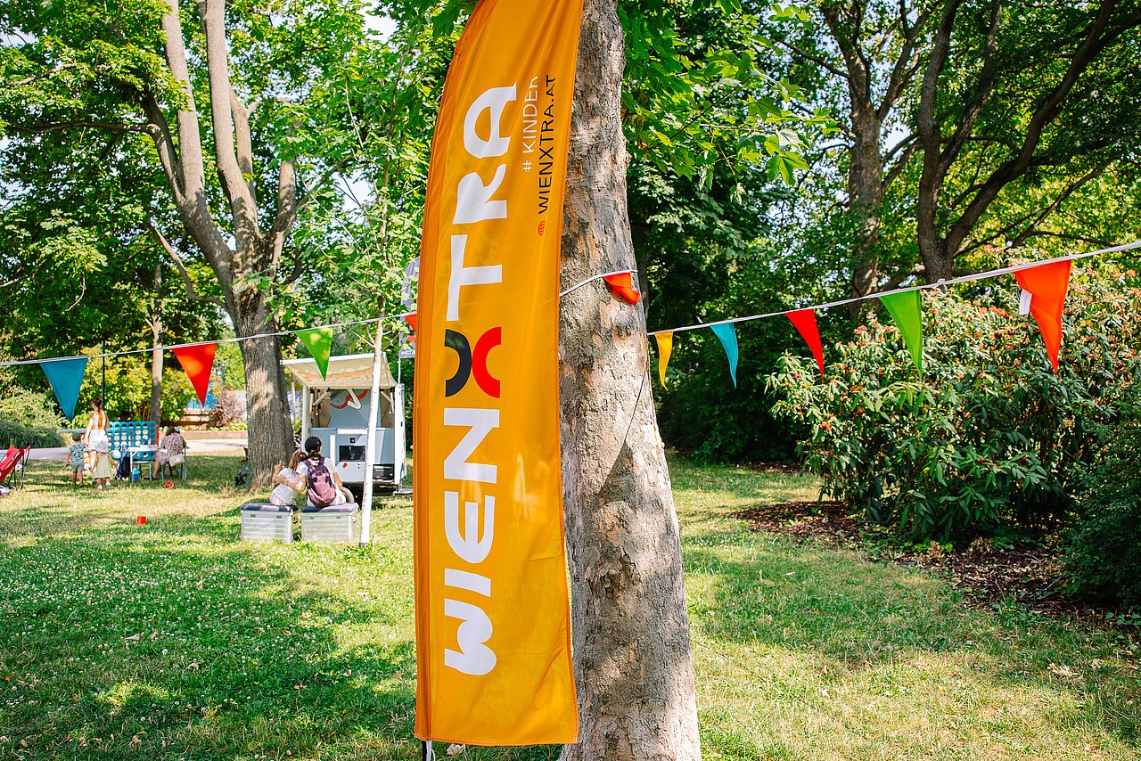 orange Wienxtra Flagge vor Baum im Park