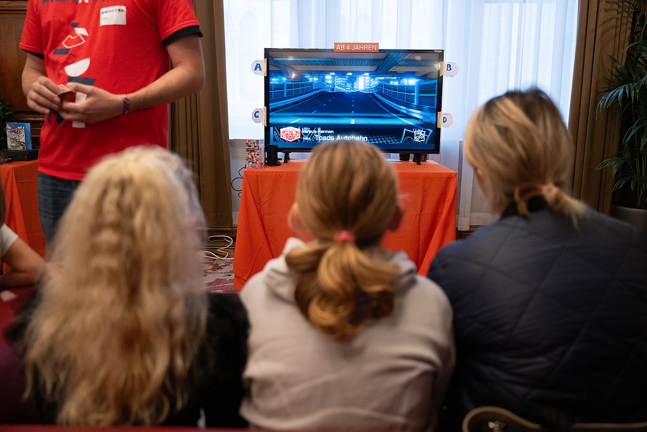 Kinder spielen im Rathaus an einer Konsole