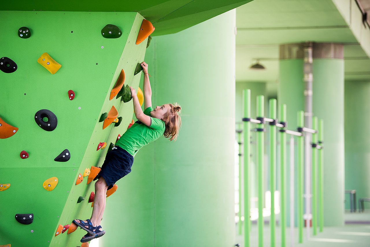 Kind klettert auf Klettergriffen draußen