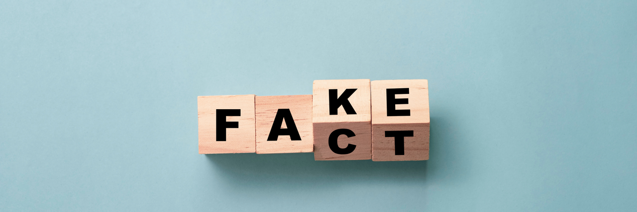 Würfel mit Buchstaben die "Fake" und "Fact" zeigen auf einem blauen Hintergrund