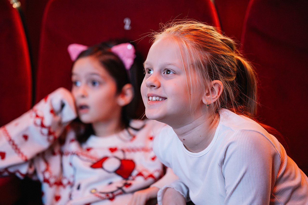 Mädchen Nahaufnahme im Kino 2 Mädchen in einem Kinosaal, seitlich aufgenommen, die aufmerksam auf die Leinwand schauen