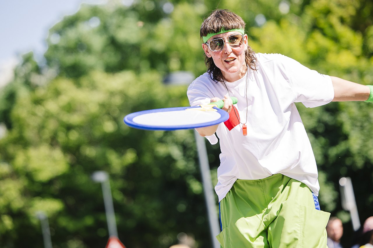 Ferienspiel_Startfest_2025_c_Aleksandra_Kawka (30) Clown-Frau mit riesigem Tennisschläger im Park