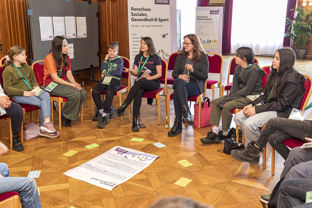 Jugendliche sitzen in einem Sesselkreis und diskutieren.