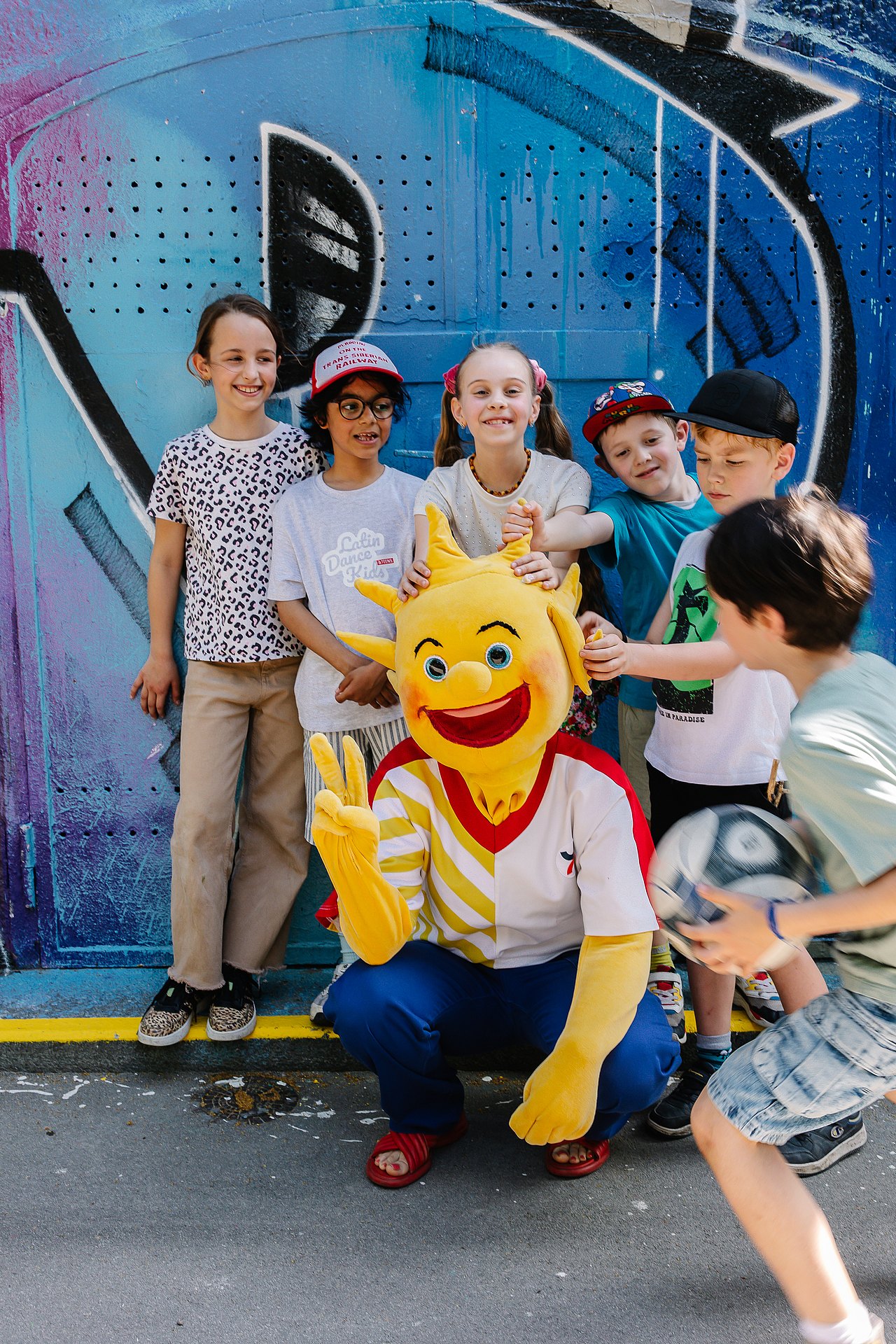 Kinder mit Holli vor einer Graffiti-Wand