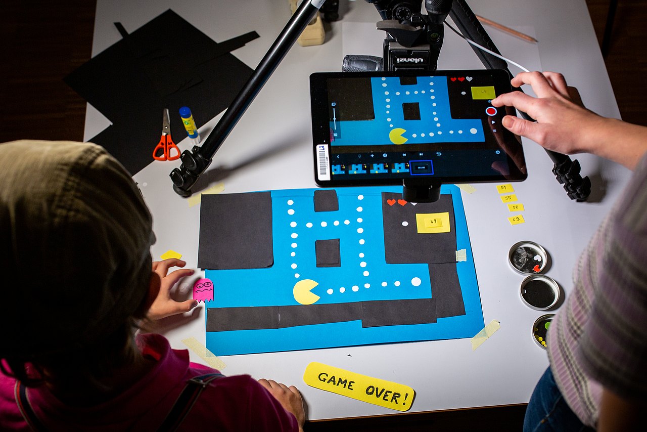 Zwei Jugendliche erstellen eine Stop-Motion-Animation mit ausgeschnittenem Papier und einem iPad.