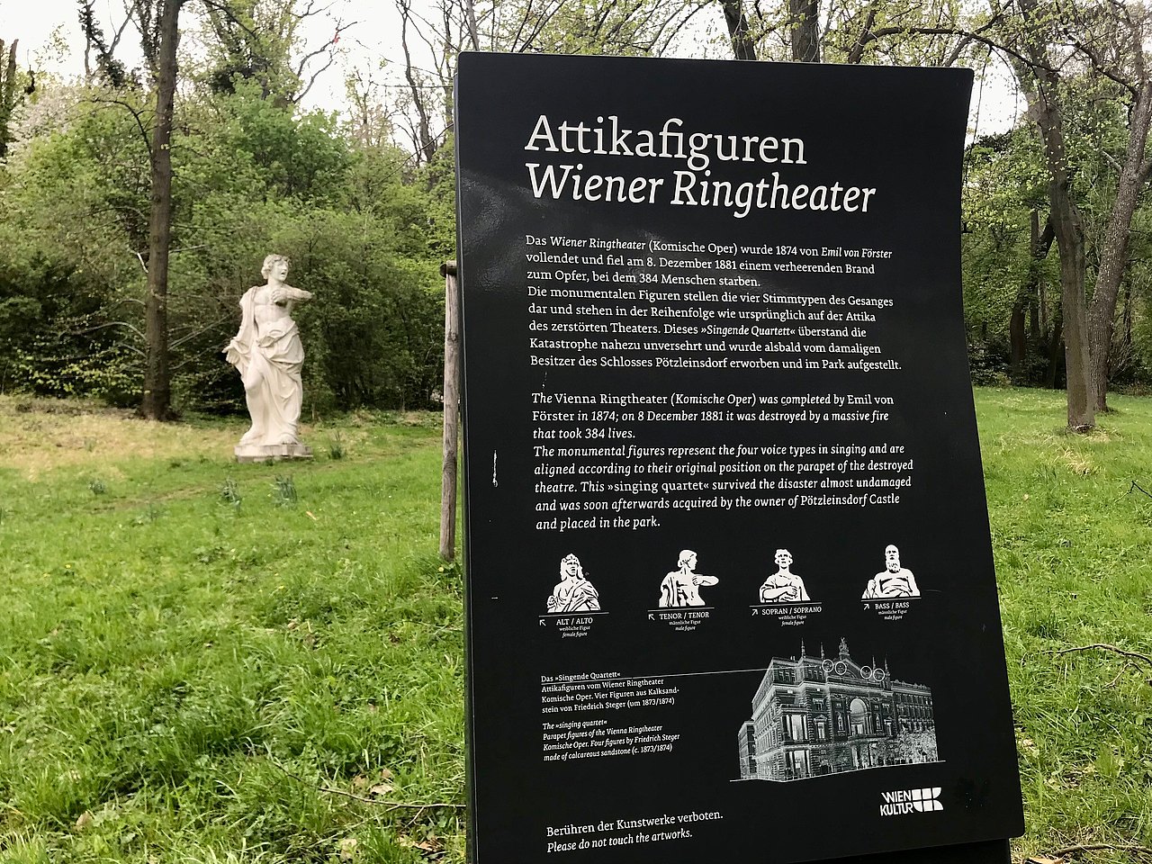 Texttafel: Attikafiguren. Wiener Ringtheater. Das Wiener Ringtheater (Komische Oper) wurde 1874 von Emil von Förster vollendet und fiel am 8. Dezember 1881 einem verheerenden Brand zum Opfer, bei dem 384 Menschen starben. Die monumentalen Figuren stellen die vier Stimmtypen des Gesanges dar und stehen in der Reihenfolge wie ursprünglich auf der Attika des zerstörten Theaters. Dieses "Singende Quartett" überstand die Katastrophe nahezu unversehrt und wurde alsbald vom damaligen Besitzer des Schlosses Pötzleinsdorf erworben und im Park aufgestellt. [Englische Übersetzung] Alt: weibliche Figur, Tenor: männliche Figur, Sopran: weibliche Figur, Bass: männliche Figur [mit bebilderten Büsten]. [Englische Übersetzung] Das "Singende Quartett". Attikafiguren vom Wiener Ringtheater Komische Oper. Vier Figuren aus Kalksandstein von Friedrich Steger (um 1873/1874) [Englische Übersetzung]. Skizzierung des Ringtheaters mit Kennzeichnung der vier Figuren am oberen Balkon. Hinter der Tafel steht die Tenor-Figur.