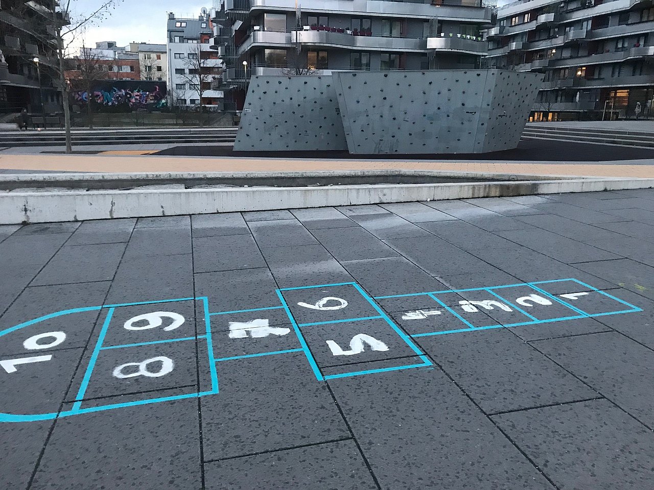 Am Boden ist ein Tempelhüpffeld, dahinter sieht man eine große Boulderwand
