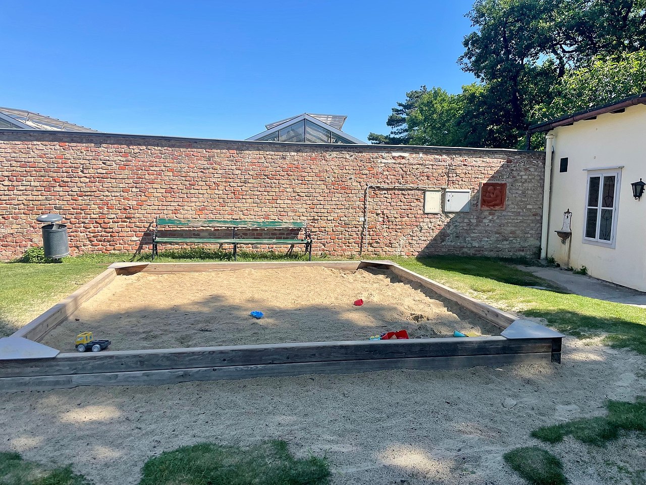 Sandkiste am Spielplatz im Belvedere Garten Sandkiste auf einer Wiese mit ein paar Sandspielgeräten drinnen