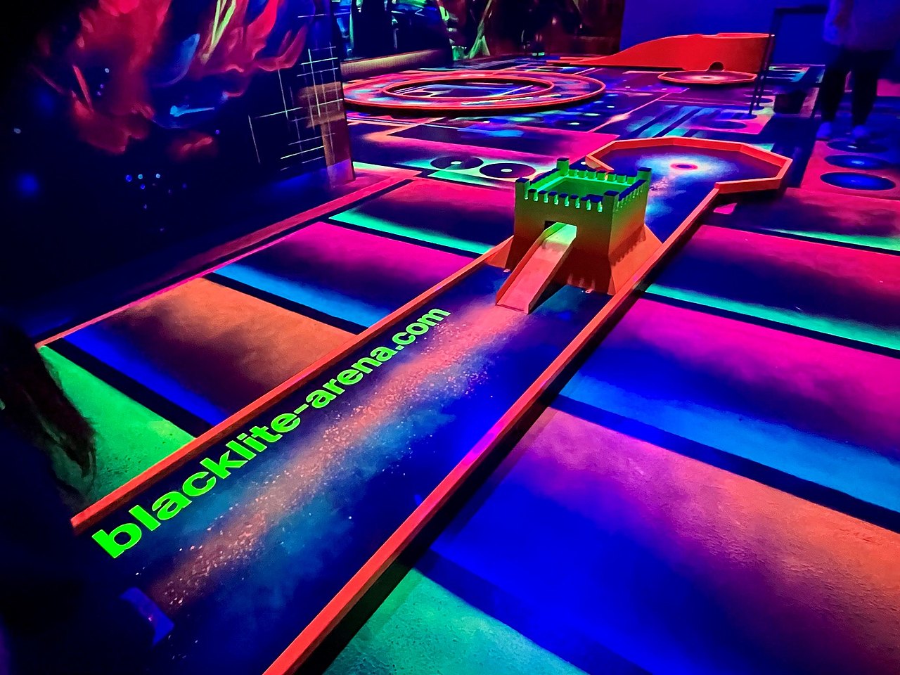 3D-Minigolfbahn in einem dunklen Raum mit Neonfarben-Zeichnungen